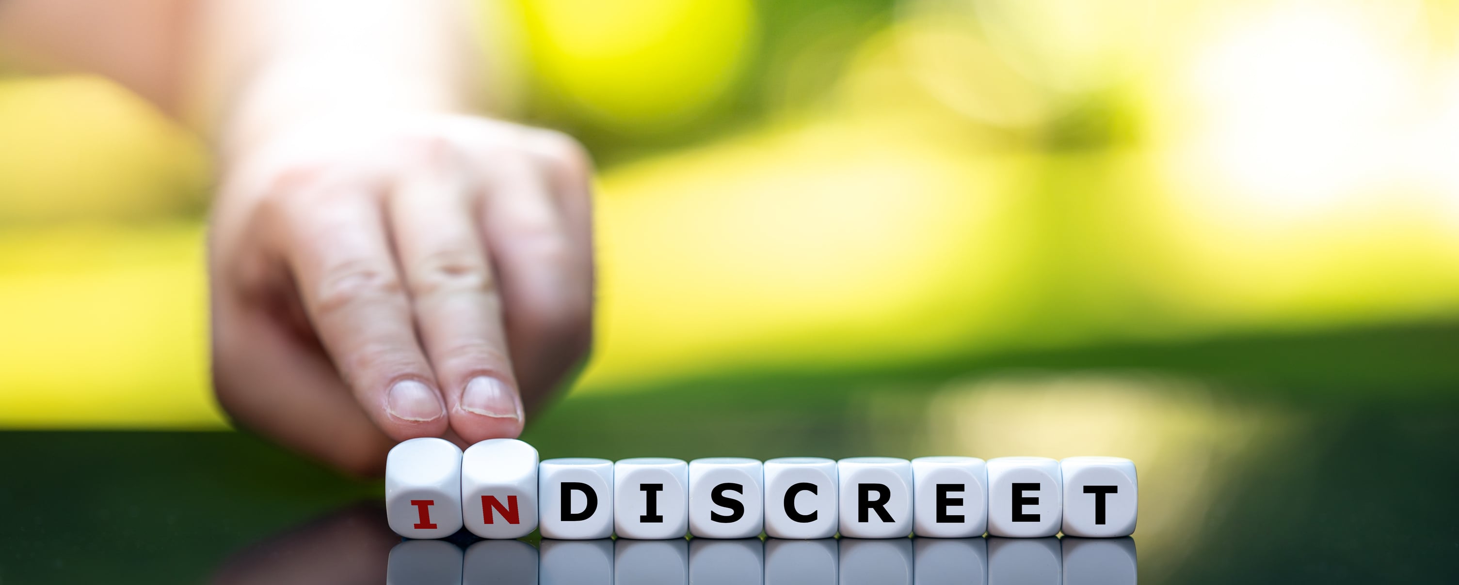 Hand turns dice and changes the word "indiscreet" to "discreet".